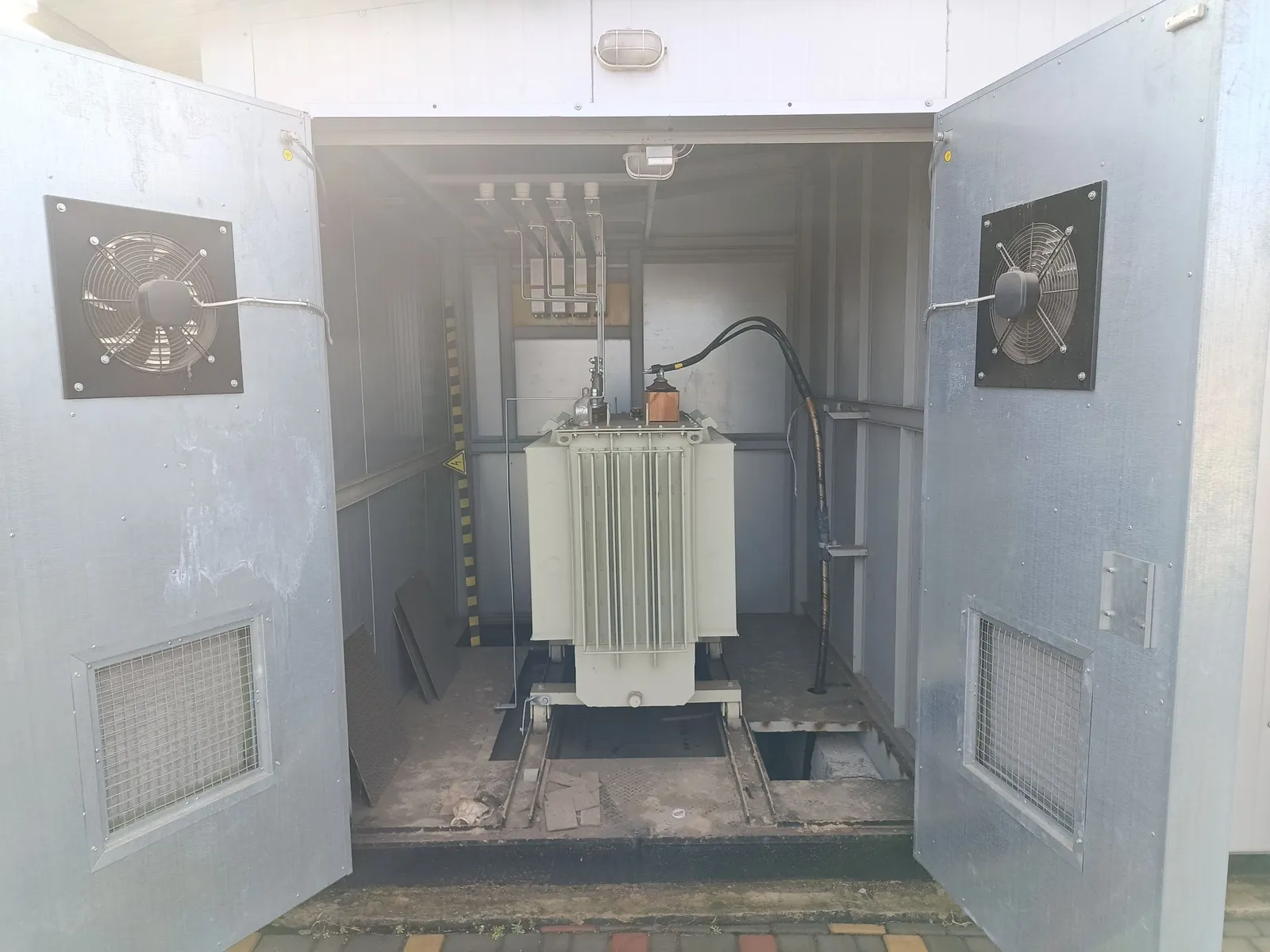 A transformer in its own bay: fans on opposite walls, rails for withdrawal