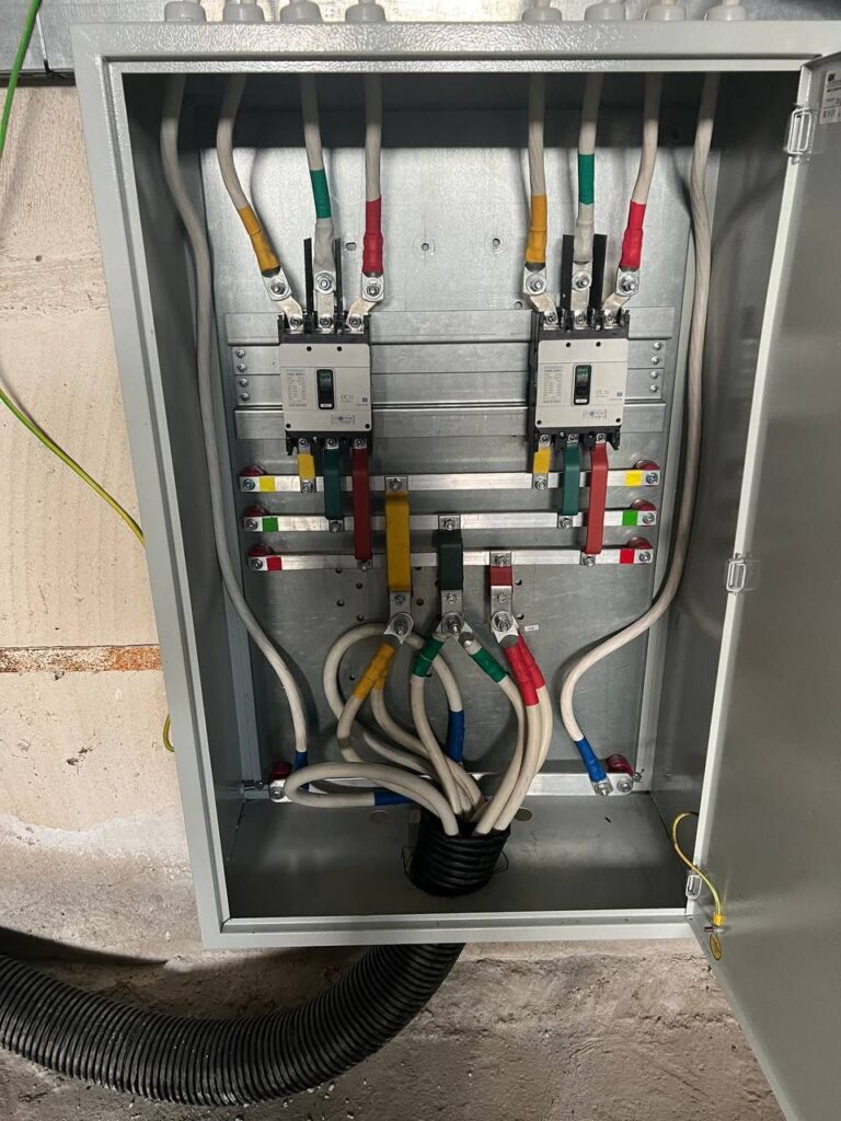 Wall-mounted 0.4 kV distribution board with two moulded case breakers and connected cables