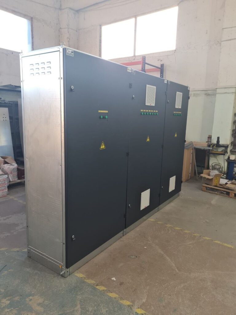 Three-section switchgear cabinet in dark enclosure with ventilation grilles in the workshop